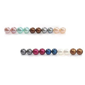 May include: A collection of colorful, round pearls in various shades, including pink, green, brown, and silver. The pearls are arranged in two rows against a white background, showcasing their diverse colors and textures.