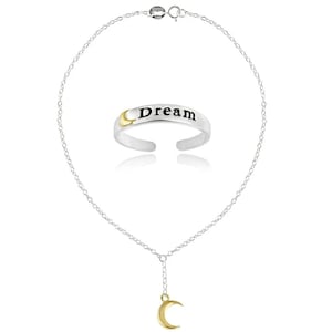 May include: A silver necklace with a gold crescent moon pendant and a silver ring with the word "Dream" and a gold crescent moon design. The jewelry is displayed on a white background.