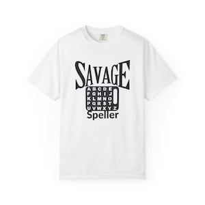 May include: A white short-sleeve t-shirt featuring a black graphic print on the chest. The design includes the word SAVAGE in large letters above a rectangular grid containing the alphabet from A to Z, with the word Speller printed below.