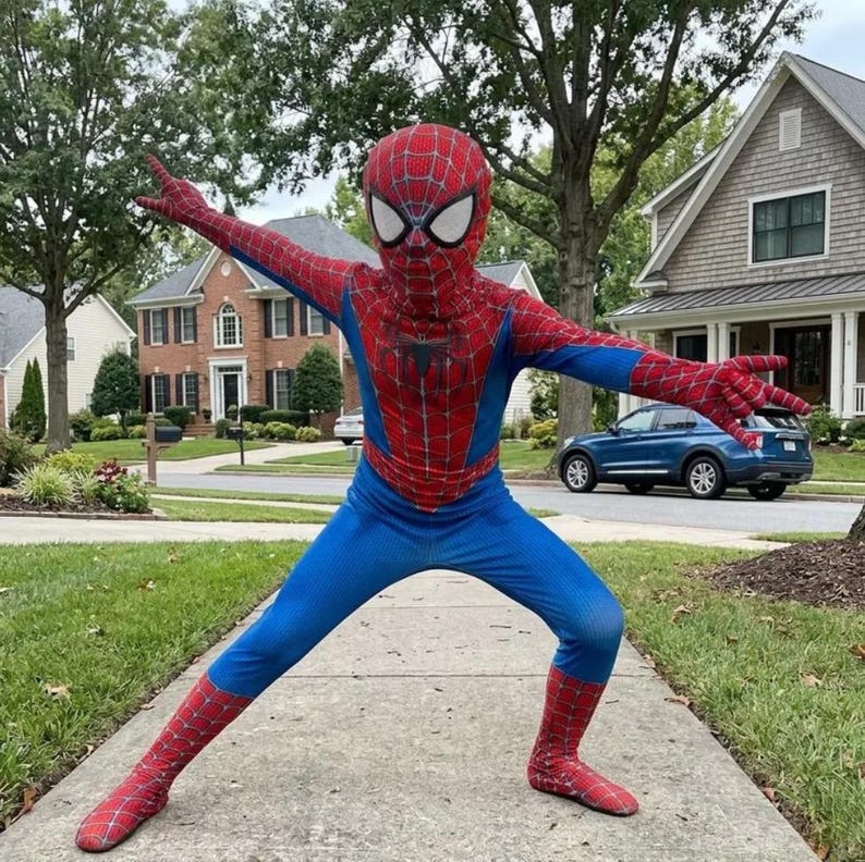Puede incluir: Una persona con un disfraz de Spider-Man posa en una acera. El disfraz es rojo y azul, con un patr&oacute;n de telara&ntilde;a en las secciones rojas. La m&aacute;scara cubre toda la cabeza, con aberturas blancas para los ojos. La persona est&aacute; en pose de superh&eacute;roe.