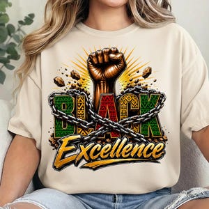 May include: Cream-colored t-shirt featuring a raised fist graphic with the words "BLACK Excellence." The word "BLACK" is in green, red, and black, with a chain wrapped around it. The word "Excellence" is in gold.