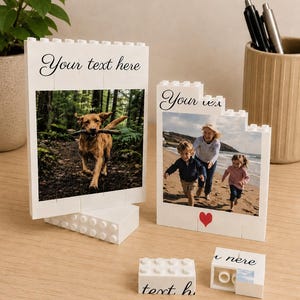 May include: White Lego-style photo frames with printed photos. One frame shows a dog with a stick, the other shows a family on a beach. The frames have the text "Your text here" and a red heart.