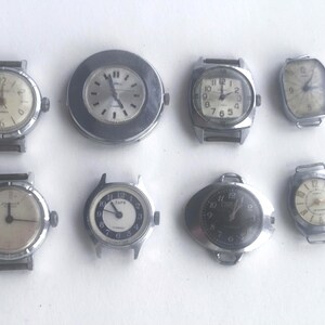 Puede incluir: Una colección de ocho relojes de pulsera vintage con diversas formas de esfera y estilos de correa. Los relojes tienen cajas de metal plateado. Las esferas muestran números y agujas, algunas son redondas, otras rectangulares u ovaladas.