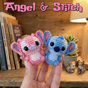 Può includere: Due piccole figure amigurumi all'uncinetto, una rosa e una blu, con grandi orecchie e occhi neri. La figura rosa ha la pancia e l'interno delle orecchie più chiari, mentre quella blu ha il naso blu scuro. È visibile il testo Angel & Stitch.