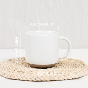 Op de afbeelding: Een witte keramische mok met een gespikkelde afwerking en een bruine onderkant. De mok heeft een handvat aan de zijkant en is voorzien van afmetingen van 8,8 cm hoog en 8,8 cm breed, met een totale breedte van 12 cm inclusief het handvat.