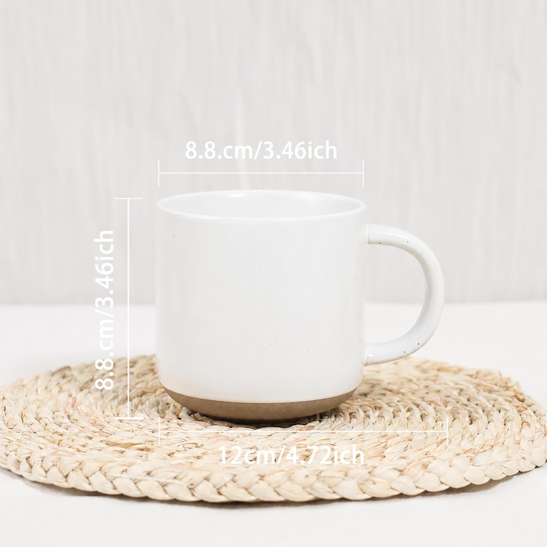 Op de afbeelding: Een witte keramische mok met een gespikkelde afwerking en een bruine onderkant. De mok heeft een handvat aan de zijkant en is voorzien van afmetingen van 8,8 cm hoog en 8,8 cm breed, met een totale breedte van 12 cm inclusief het handvat.