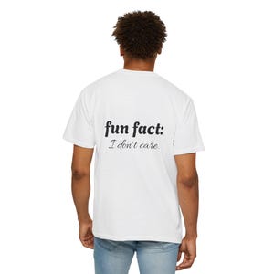 Op de afbeelding: Wit T-shirt met de tekst "fun fact: I don't care" in het zwart gedrukt. Het shirt heeft een casual stijl, geschikt voor dagelijks gebruik. De persoon draagt een blauwe spijkerbroek.