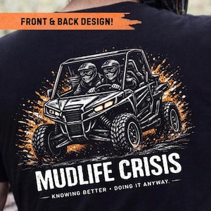 May include: A black t-shirt featuring a graphic of two figures wearing helmets driving an off-road vehicle through mud. The text reads FRONT & BACK DESIGN! at the top and MUDLIFE CRISIS KNOWING BETTER • DOING IT ANYWAY. at the bottom.