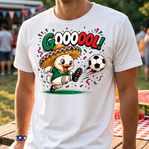May include: A white t-shirt featuring a graphic of a cartoon duck wearing a sombrero and a green jersey, kicking a soccer ball. The text GOOOOOL is printed above the duck in green, white, and red colors, surrounded by colorful confetti.