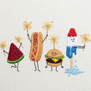 May include: Embroidered image of a watermelon slice, hot dog, hamburger, and ice lolly, each with smiling faces and holding sparklers. The watermelon is red with a green rind. The hot dog is in a bun with mustard. The burger has a cheese slice. The ice lolly is red, white, and blue.