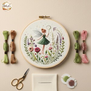 K&ouml;nnte beinhalten: Stickset mit einem Feen-Design. Das Set enth&auml;lt einen Holzrahmen, Stickgarn in verschiedenen Farben, eine Schere, eine Nadel und Stoff. Die Fee tr&auml;gt ein gr&uuml;nes Kleid, umgeben von Blumen. Ideal f&uuml;r Bastelprojekte.