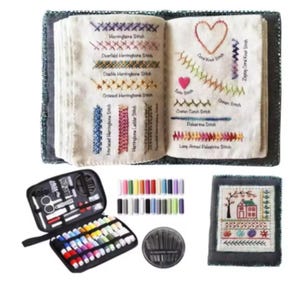 Könnte beinhalten: Ein offenes Buch zeigt verschiedene Stickstich-Beispiele mit farbigen Fäden. Ein schwarzes Etui mit Nähwerkzeugen, Garnrollen und einem Nadelset ist ebenfalls zu sehen. Ein kleines, gerahmtes Stickbild vervollständigt das Bild.