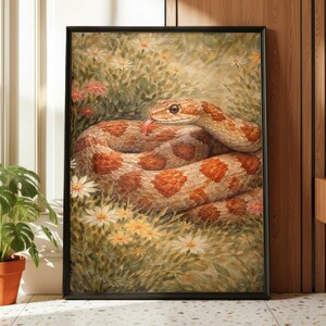 May include: A framed art print depicting a snake in a field of flowers. The snake has a tan and orange pattern, with its tongue out. The artwork is in a black frame. The print is a nature-themed piece, suitable for home decor.