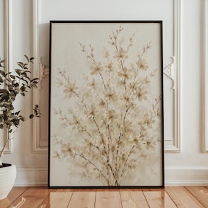Könnte beinhalten: Ein gerahmter Blumendruck mit einem Bouquet aus beigefarbenen Blumen mit braunen Stielen auf cremefarbenem Hintergrund. Das Kunstwerk befindet sich in einem schwarzen Rahmen vor einer weißen Wand und einem Holzboden.