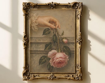 May include: A framed vintage-style print featuring a hand holding pink roses. The artwork is set in an ornate gold frame with detailed scrollwork. The background has a neutral tone, enhancing the soft colors of the roses.