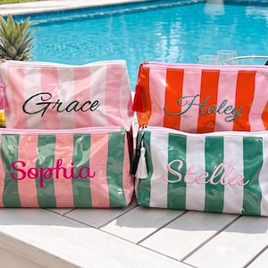 May include: Four rectangular zippered pouches with vertical stripes in pink and white, orange and white, pink and green, and green and white. Each pouch features a tassel on the zipper and is embroidered with the names Grace, Haley, Sophia, or Stella.