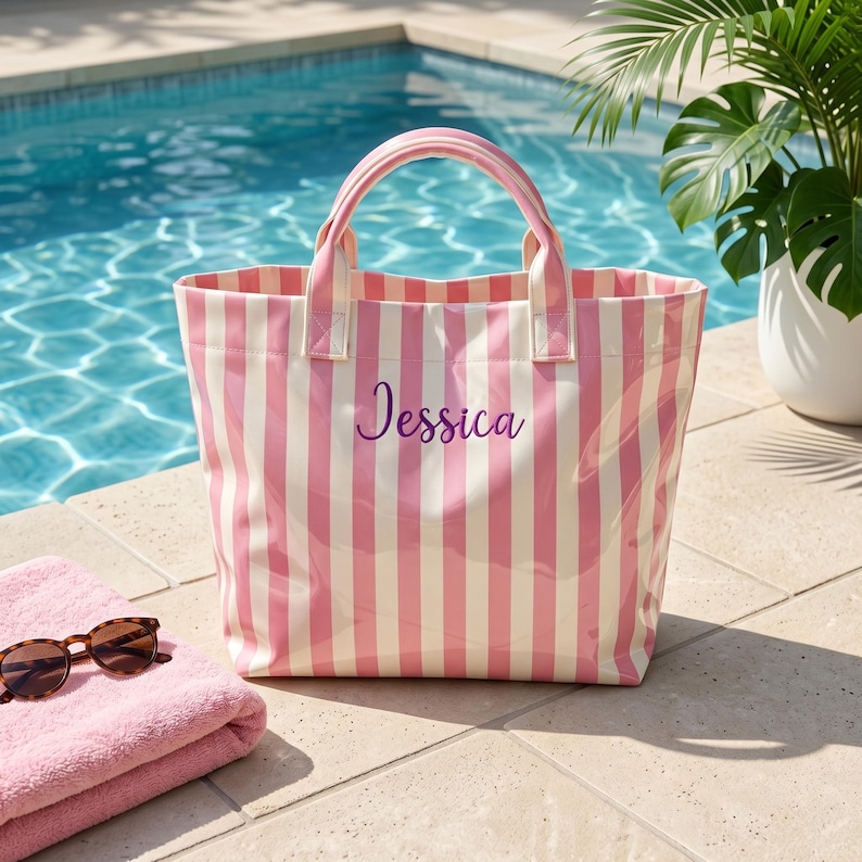 May include: A tote bag featuring vertical pink and white stripes with the name Jessica written in purple script on the front. The bag has two matching striped handles and a structured rectangular shape, presented as a functional accessory.