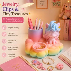 May include: A desk tidy in pastel shades, featuring a unicorn ornament, pen pot, and a small dish for jewellery. The image shows a pink notebook, hair clips, a bracelet, and a ring. Text reads "Jewelry, Clips & Tiny Treasures."