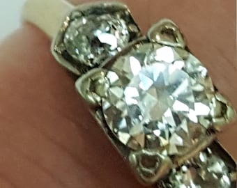 May include: A gold ring with three diamonds. The center diamond is larger than the two side diamonds.