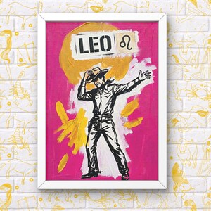 May include: A framed artwork featuring a cowboy illustration on a pink background. The word "LEO" is above the cowboy, along with the Leo zodiac symbol. The artwork has a white frame and yellow paint strokes.