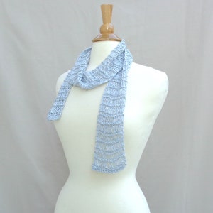 May include: A light blue knitted scarf on a white mannequin. The scarf is made of a delicate, open-weave pattern.