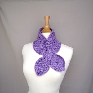May include: A purple knitted cowl neck scarf with a unique leaf-shaped design. The scarf is displayed on a white mannequin.