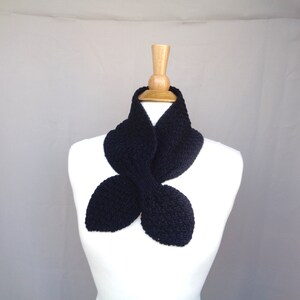 May include: A black knitted infinity scarf with a unique butterfly shape. The scarf is made from a soft, textured yarn and is perfect for adding a touch of style to any outfit.