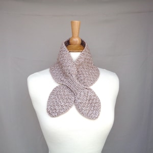 May include: A brown and white knit infinity scarf with a twisted design. The scarf is displayed on a white mannequin.