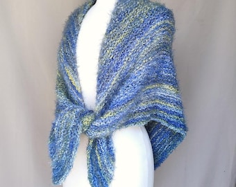 Könnte beinhalten: Ein blau-grüner Strickschal, der über einer weißen Schaufensterpuppe drapiert ist. Der Schal ist vorne gebunden und zeigt ein strukturiertes, flauschiges Garn. Die Farbpalette umfasst Blau- und Grüntöne.