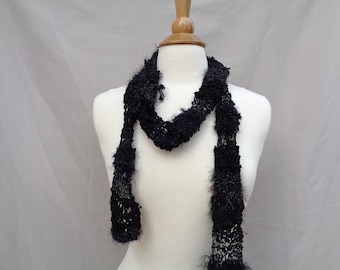 May include: A black fuzzy scarf with a textured knit design. The scarf is draped over a white mannequin.