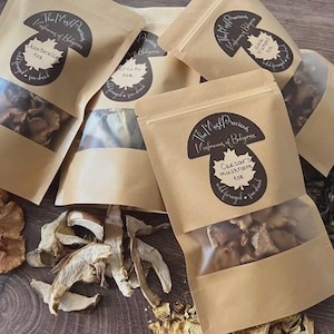 May include: A collection of kraft paper bags filled with dried mushrooms, some with transparent panels. The bags feature labels with mushroom designs and text, such as "Chanterelle" and "Caesar's mushroom". Loose dried mushrooms are scattered around the bags.