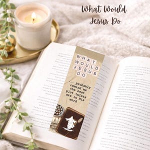 Peut inclure: Un marque-page avec le texte "What Would Jesus Do" et une citation sur les rebondissements de l'histoire dans Sa parole. Le marque-page est placé dans un livre ouvert, avec une bougie allumée et de la verdure décorative en arrière-plan. Le thème est chrétien.