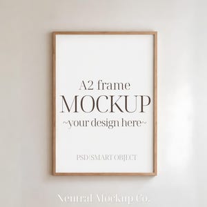 May include: A2 frame mockup with a light brown wooden frame. The white interior displays the text "MOCKUP ~your design here~". The words "PSD SMART OBJECT" and "Neutral Mockup Co." are also visible.