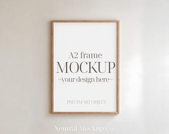 Pode incluir: Maquete de moldura A2 com uma moldura de madeira castanha clara. O interior branco exibe o texto "MOCKUP ~your design here~". As palavras "PSD SMART OBJECT" e "Neutral Mockup Co." também são visíveis.