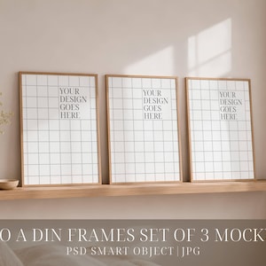 May include: A set of three vertical rectangular wooden frames arranged side by side. Each frame contains a white paper insert with a black grid pattern and the black text "YOUR DESIGN GOES HERE" centered in the upper portion of the grid.