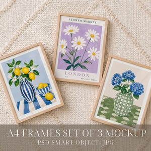 May include: Three A4 wooden frames containing botanical art prints. One print shows yellow lemons in a blue and white striped vase, another features white daisies on a purple background with text reading FLOWER MARKET LONDON, and the third displays blue hydrangeas in a green checkered vase.