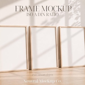 May include: Three wooden picture frames with white matting lean against a neutral-colored wall. The frames are rectangular with a light wood finish. The text "FRAME MOCKUP ISO A DIN RATIO" is at the top. The bottom text reads "Neutral Mockup Co."