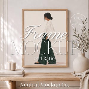 May include: A framed art print mockup featuring a woman in a white top and green pants. The frame is light brown, and the artwork is displayed on a wooden table with decorative items. Text on the frame reads "Frame Mockup" and "3x4 Ratio".