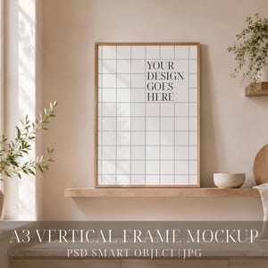 Pode incluir: Uma moldura vertical A3 com acabamento em madeira clara, apresentando um fundo com padrão de grade branca e o texto preto "YOUR DESIGN GOES HERE" centralizado no interior. A moldura está posicionada numa prateleira de madeira.
