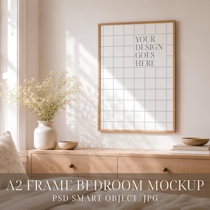 Könnte beinhalten: Ein vertikaler, rechteckiger Holzrahmen an einer Wand, der ein weißes Poster mit einem schwarzen Gittermuster und dem Text YOUR DESIGN GOES HERE enthält. Der Rahmen befindet sich über einer hölzernen Kommode mit zwei Schubladen und einer weißen Vase.