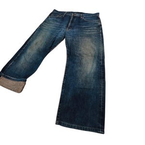 May include: Blue denim jeans with a wide leg design. The jeans have a classic five-pocket style and a button and zipper closure. The denim has a faded wash, giving the jeans a vintage look.