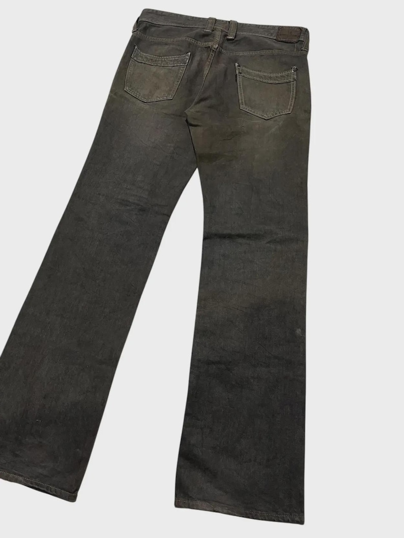 K&ouml;nnte beinhalten: Dunkelgraue Jeans mit klassischem F&uuml;nf-Taschen-Design. Die Jeans hat einen geraden Beinverlauf und ein verwaschenes Aussehen, mit sichtbaren Gebrauchsspuren an den Ges&auml;&szlig;taschen und Knien. Die Jeans wird von hinten gezeigt.