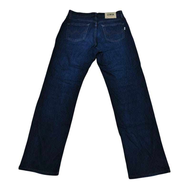 May include: Dark blue denim jeans with a classic five-pocket design. The jeans have a straight leg cut and feature the brand name "Edwin" on a back patch. The back pockets have a distinctive curved design.