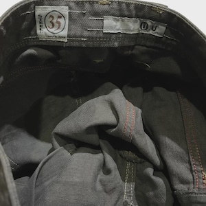 K&ouml;nnte beinhalten: Nahaufnahme der Innenseite einer grauen Jeans. Die Jeans hat ein Gr&ouml;&szlig;enetikett 35, und die N&auml;hte sind in Rot und Wei&szlig; sichtbar. Die Jeans wird in Japan hergestellt.