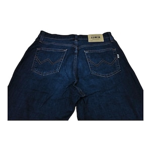 May include: Dark blue denim jeans with a classic five-pocket design. The back pockets feature a unique stitched pattern. The brand name "EDWIN" is visible on a leather patch at the waistband. The jeans are made of a durable denim material.