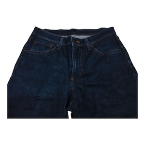 May include: Dark blue denim jeans with a classic five-pocket design. The jeans have a button and zipper closure, with visible stitching and rivets. The fabric appears to be a medium-weight denim.