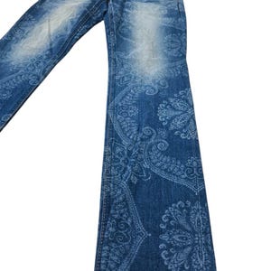 May include: Blue denim jeans with a faded wash and a paisley pattern. The jeans have a classic five-pocket design and a straight leg. The paisley pattern is a lighter shade of blue, creating a contrast against the darker denim.