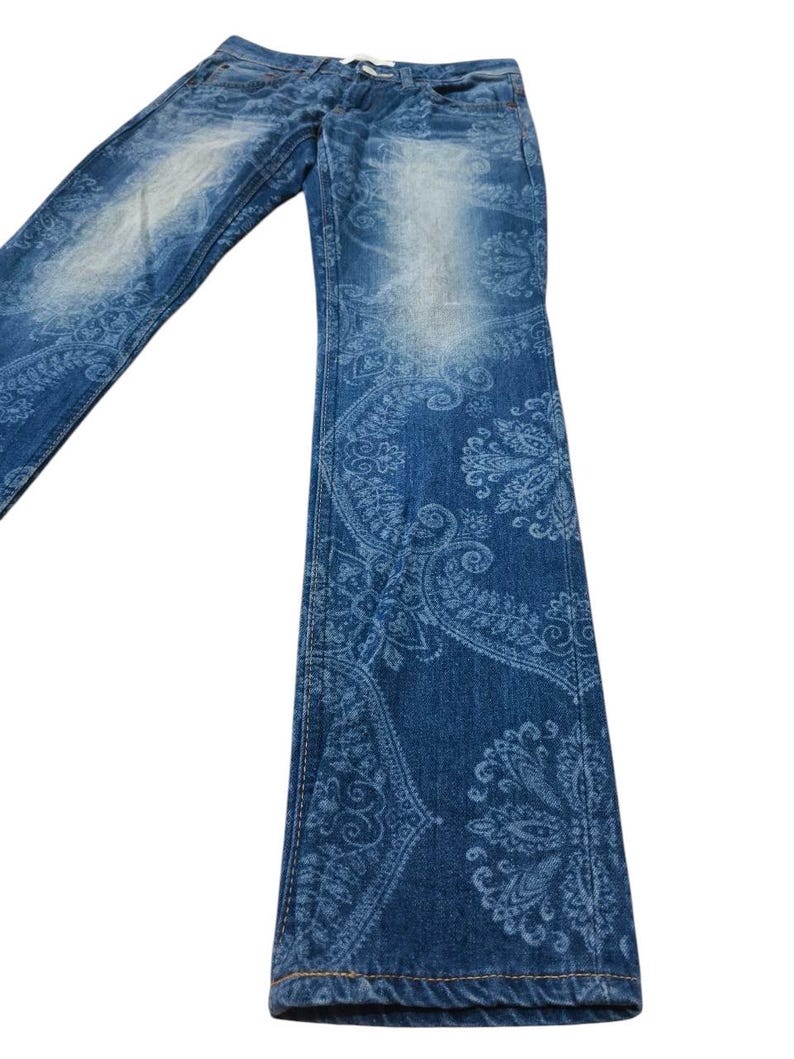 May include: Blue denim jeans with a faded wash and a paisley pattern. The jeans have a classic five-pocket design and a straight leg. The paisley pattern is a lighter shade of blue, creating a contrast against the darker denim.