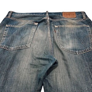 Puede incluir: Vaqueros de mezclilla azul descolorido con estilo cl&aacute;sico de cinco bolsillos. Incluye un parche de cuero marr&oacute;n con la marca "EDWIN" y una etiqueta roja en el bolsillo trasero. Los vaqueros tienen un aspecto desgastado.