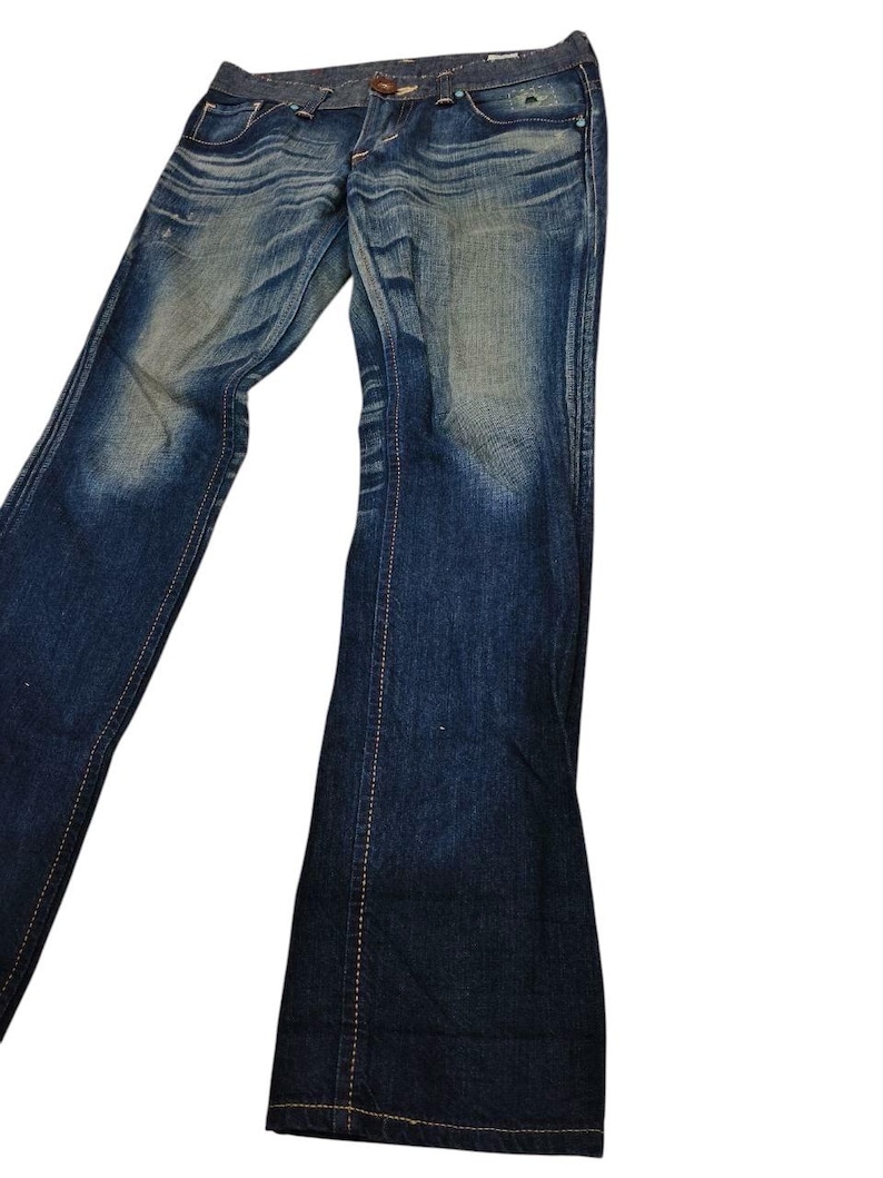 May include: Blue denim jeans with a faded wash and flared leg. The jeans have a classic five-pocket design, a button and zipper closure, and visible stitching. The denim has a worn appearance.